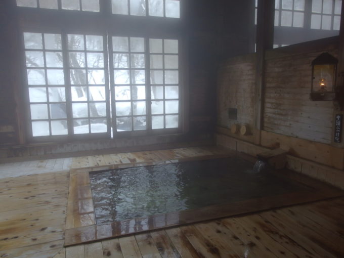 冬のランプの宿青荷温泉源泉かけ流しの大きな湯船と白銀に染まる窓