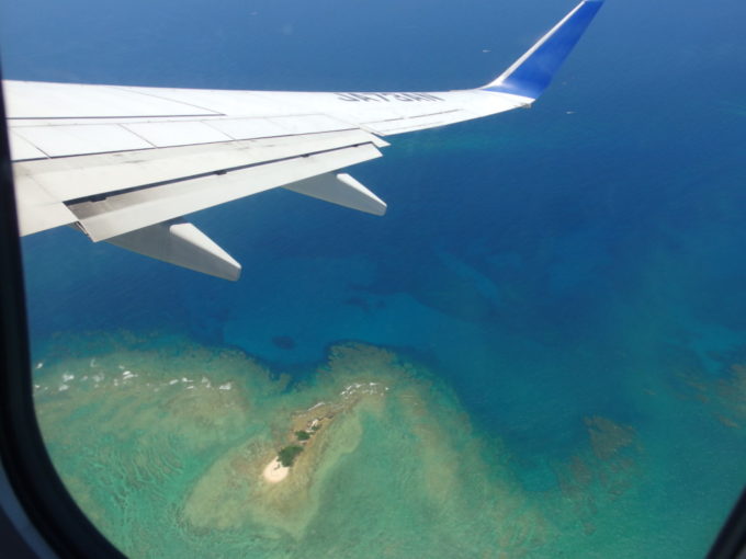 6月梅雨明けの全日空機から見下ろす沖縄の青い海と珊瑚礁