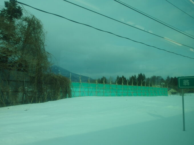 2月中旬冬の磐越西線雪原に設けられた木の仮設防雪柵