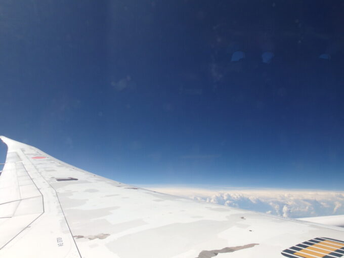 6月中旬梅雨明け直後のANA787型機羽田行き機窓を染める大空の青さ