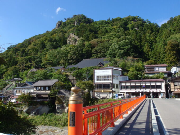 10月中旬初秋の山寺赤い欄干の橋と聳える山に建つ山寺の建物