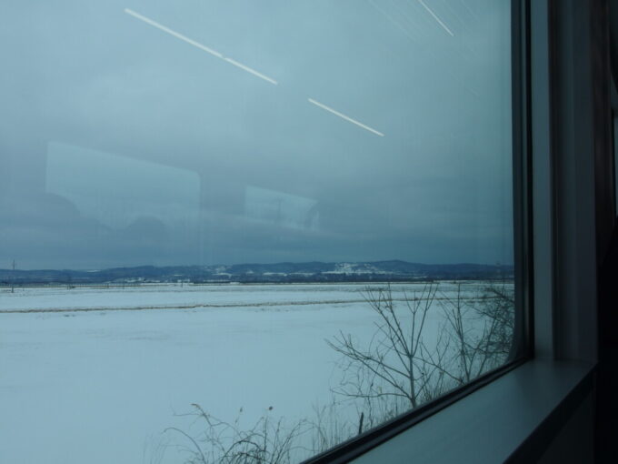 1月中旬冬の初十勝根室本線H100形電気式気動車DECMO釧路行き普通列車大きな車窓に広がる雪原