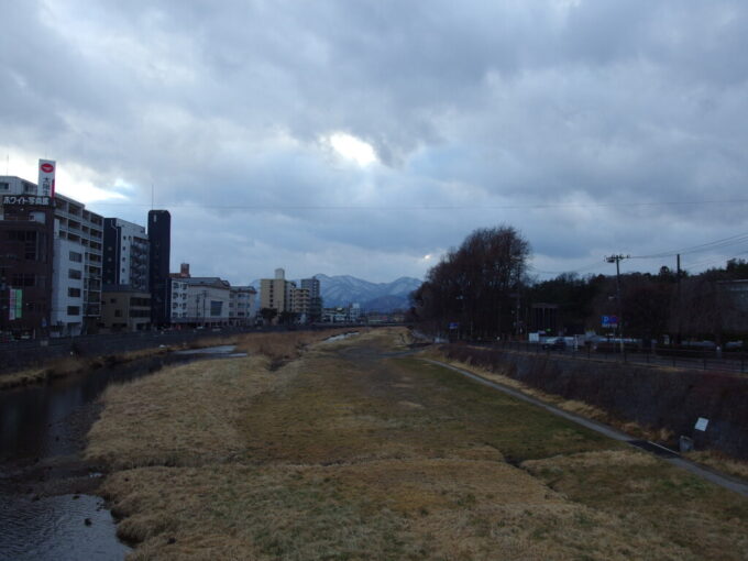 2月中旬小雨交じりの盛岡遠くに雪景色を望む枯色をした中津川の河川敷
