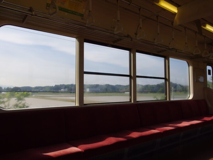 5月上旬昼下がりの東北本線701系普通列車小牛田行き大きな窓に流れる初夏の長閑な田園風景