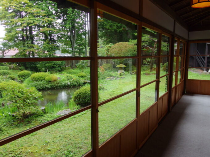 10月上旬旧中山道福島宿山村代官屋敷古き良き木のサッシから眺める緑豊かな築山泉水式庭園