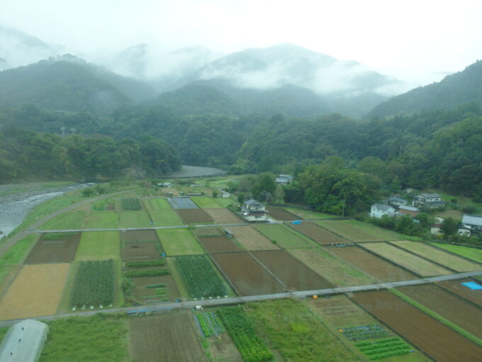 10月下旬雨の中央本線E353系特別急行かいじ号甲府行きは田んぼの広がる谷を鉄橋で一跨ぎ