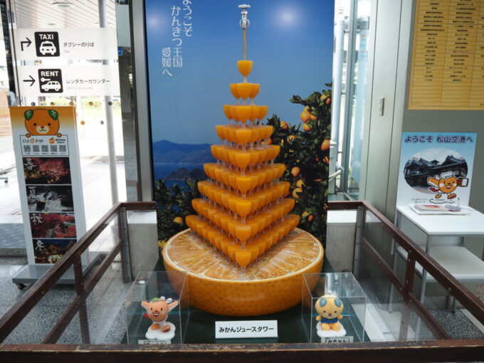 5月中旬の瀬戸内松山空港に聳えるみかんジュースタワーとみきゃん、松山空港イメージキャラクターのまっくう