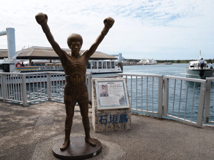 6月中旬梅雨明け後の石垣島ユーグレナ石垣港離島ターミナルで拳を突き上げる具志堅さん