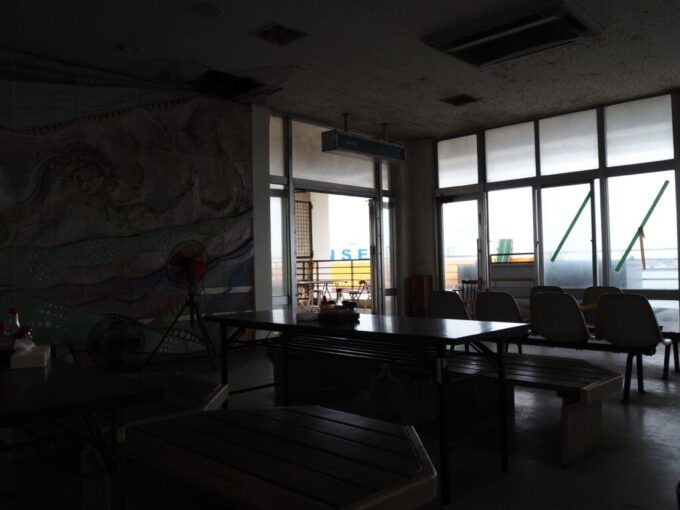 6月中旬梅雨明け後の八重山石垣島浜崎町旧石垣港ターミナル2階の食事処みなと売店昼なお薄暗いロビーから眺める入港する貨物船