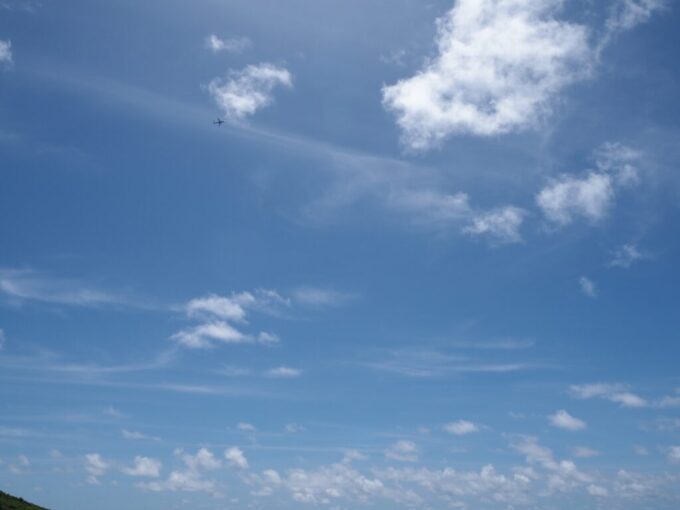 6月中旬梅雨明け後の八重山石垣島真栄里ビーチから見上げる南ぬ島石垣空港を離陸し大空へと飛翔する飛行機