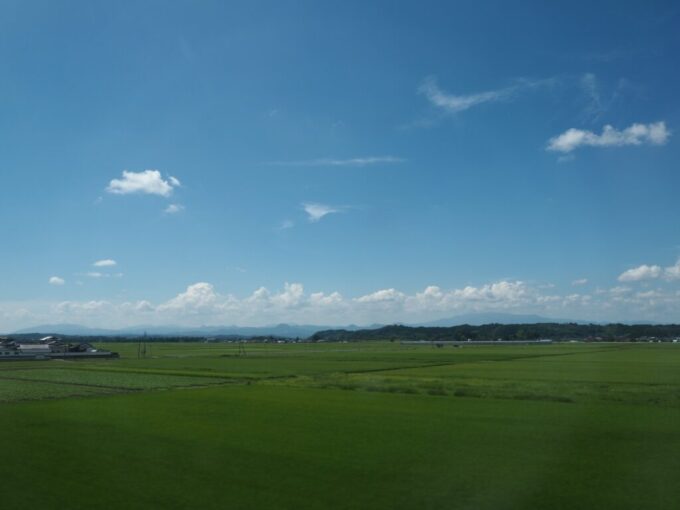8月上旬東北新幹線E5系はやぶさ号新青森行き車窓から眺めるどこまでも広がる田園とその先に横たわる栗駒山