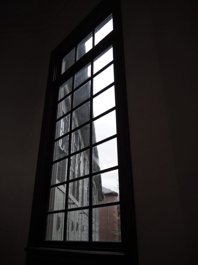 9月下旬涼やかな信州松本あがたの森公園旧松本高等学校本館階段の踊り場の窓からはゆらぎのある古いガラス越しの情景