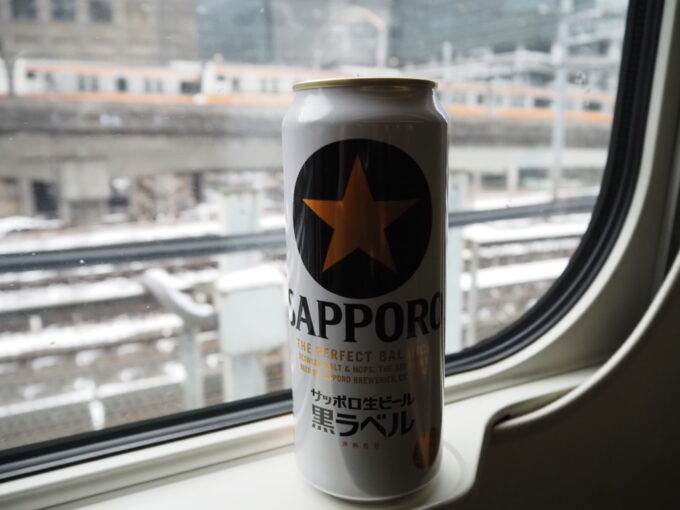 2月上旬東北新幹線E5系やまびこ号盛岡行き東京駅を発車し降る雪と並走する中央線を眺めつつサッポロ黒ラベル金星で旅立ちの祝杯を