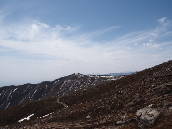 4月中旬春うららの那須岳主峰茶臼岳山頂へと向かう登山道から見下ろす白い雪の残る南月山