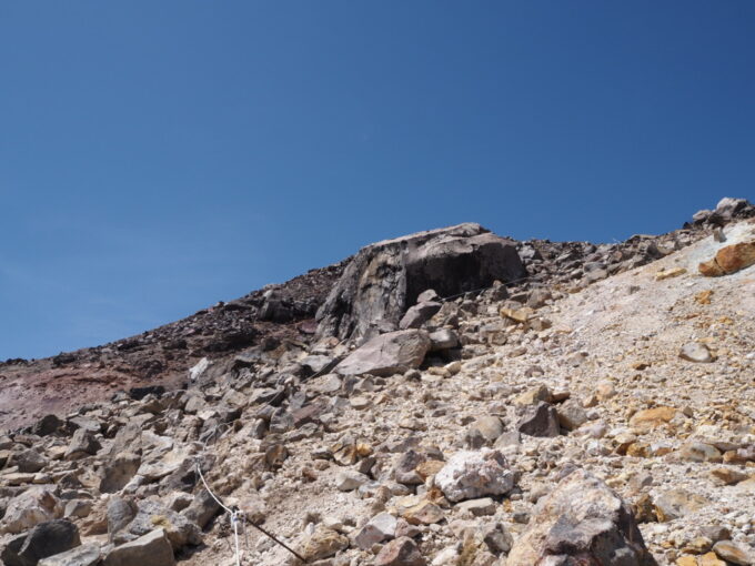 4月中旬春うららの那須岳主峰茶臼岳山頂へと向かう登山道頭上に大岩の圧迫感を感じつつ手も使って岩だらけの道を登ってゆく
