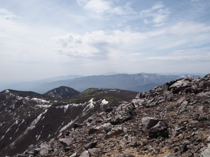 4月中旬春うららの那須岳主峰茶臼岳山頂へと向かう登山道頂上間近からうっすらと望む日光の山並み