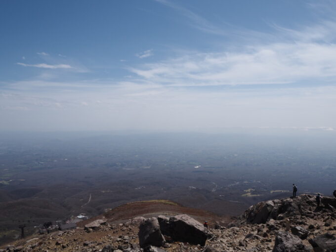 4月中旬春うららの那須岳主峰茶臼岳山頂へと向かう登山道岩場を登り振り返れば雄大な那須野が原を一望のもとに